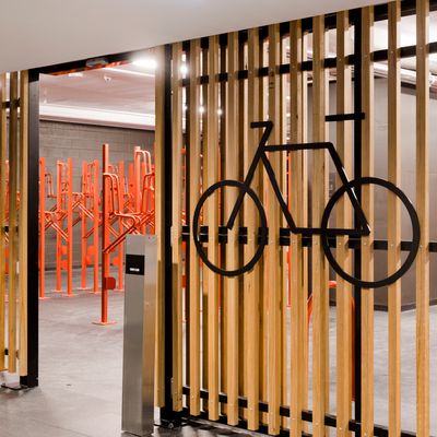 A modern end-of-trip facilities area in an office building, with a bicycle storage seen through wooden slats secured by a card reader system.